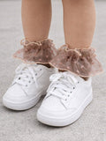 White sneakers with frilly, pink heart-patterned ankle socks on a child's feet.