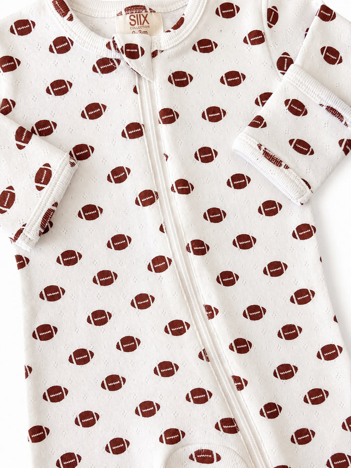 White baby onesie with a football pattern, featuring a zipper and soft cuffs. Ideal for infants aged 0-3 months.