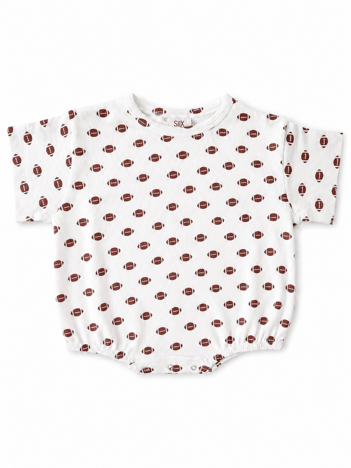 White baby onesie with a football pattern, featuring short sleeves and snap closure at the bottom.