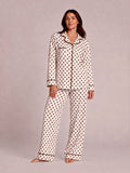 Woman in polka dot pajamas poses confidently against a light background. Casual, cozy sleepwear fashion.