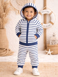 Smiling toddler in a striped hoodie and pants, standing on a beach-themed background, with decor elements nearby.