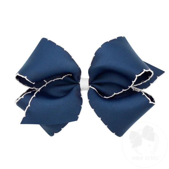 Navy blue hair bow with white trim on a white background