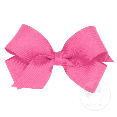 A pink grosgrain hair bow attached to a clip, displayed on a white background.
