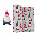 Plush gnome toy beside a fabric featuring festive gnome patterns on a light gray background.