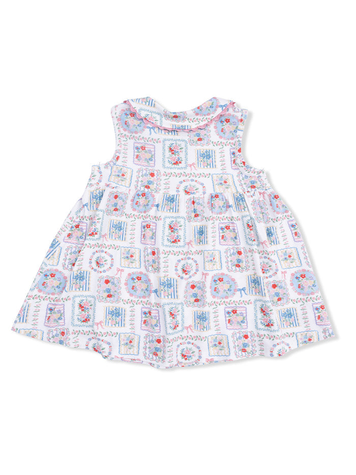 Floral-patterned sleeveless dress with a ruffled neckline, featuring colorful squares and flowers on a white background.