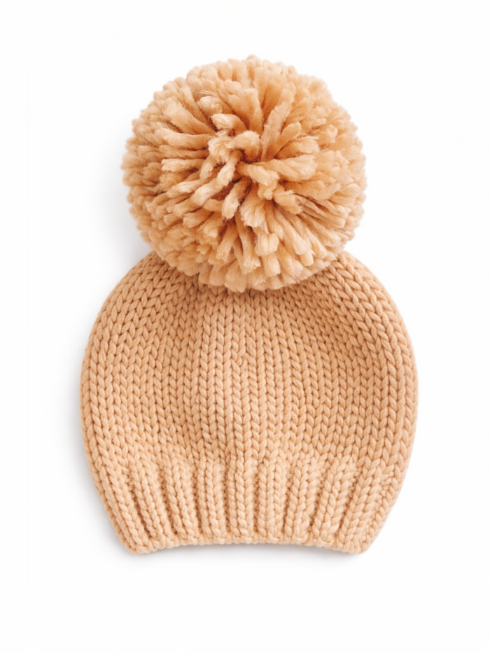 Cozy beige knitted beanie with a large pom-pom on top, ideal for winter wear.
