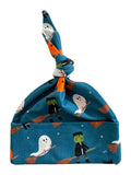 Blue hat with ghosts, Frankensteins, and brooms, featuring a knotted top for a playful Halloween theme.