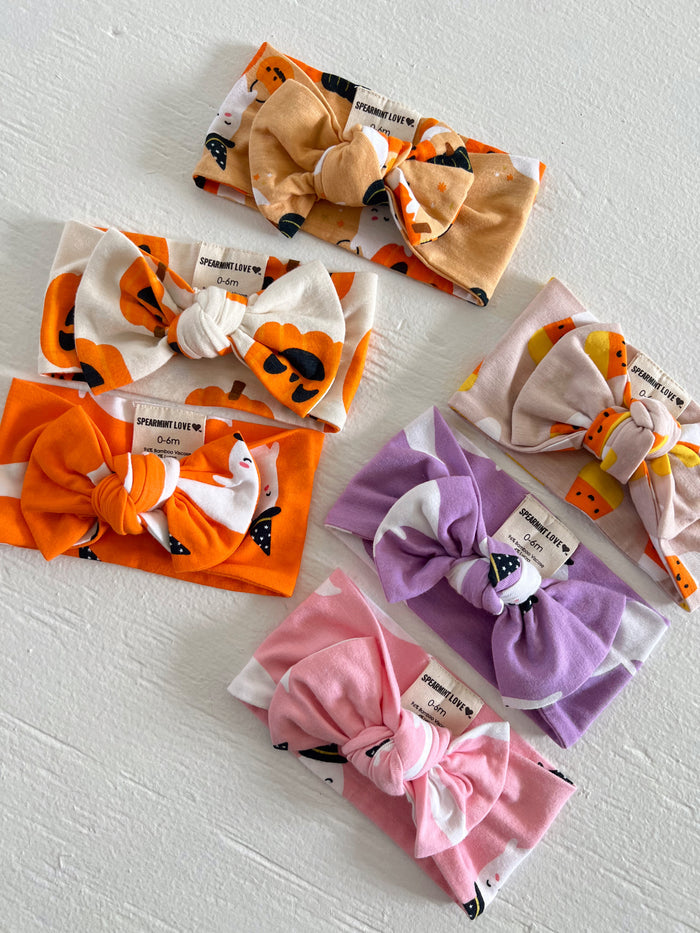 A collection of colorful baby headbands in various patterns, including pumpkins and playful designs.