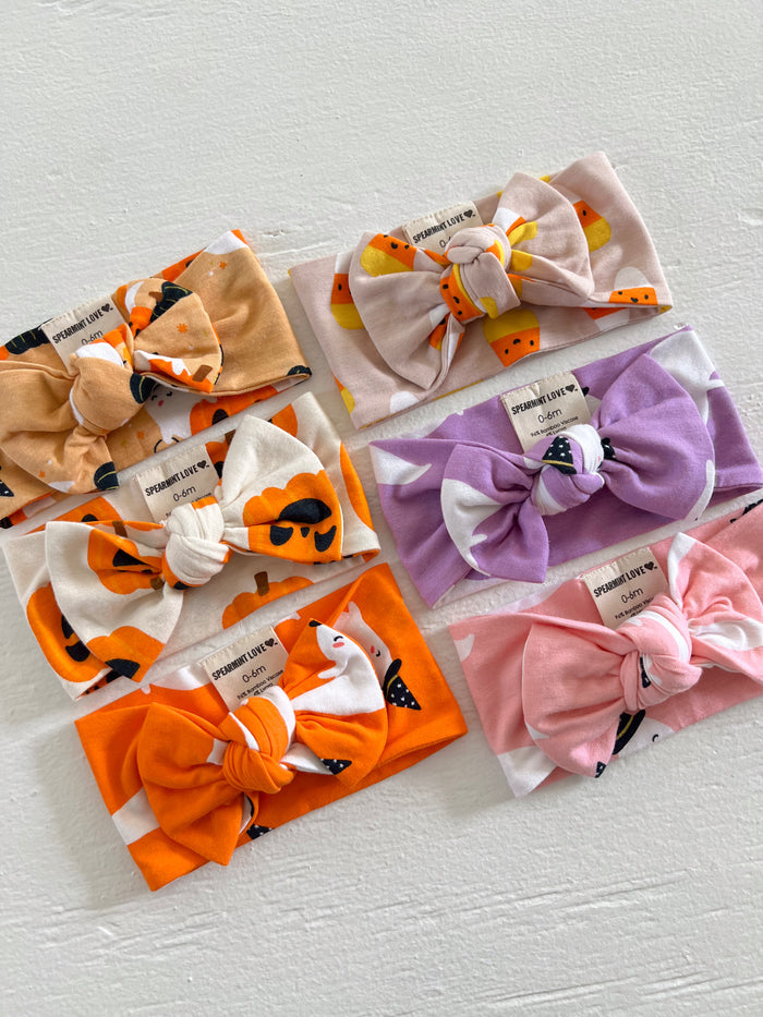 A collection of colorful patterned headbands with bows, arranged on a white surface.