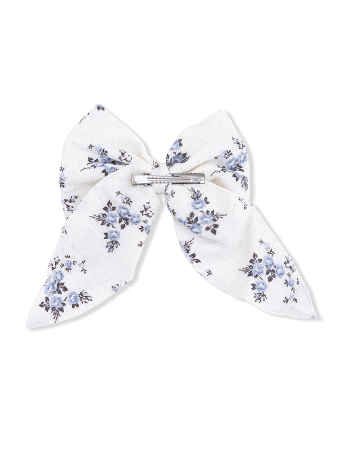 White hair bow with blue floral pattern and a silver clip at the center.