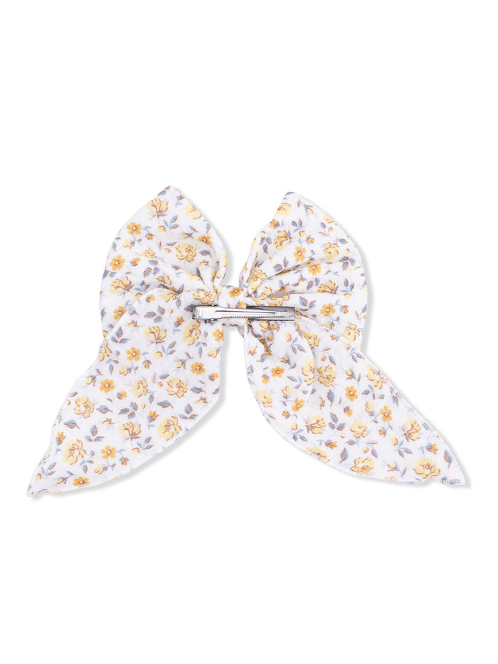Floral hair bow with yellow flowers on a white background, secured with a silver clip.