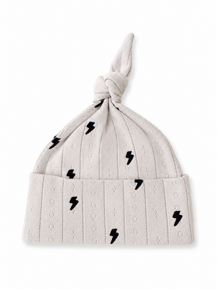 Knot-structured light gray baby hat with black lightning bolt patterns. Ideal for stylish infant wear.