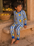 Boy in striped blue and white pajamas with lemons, sitting on a stone step next to a basket of lemons.