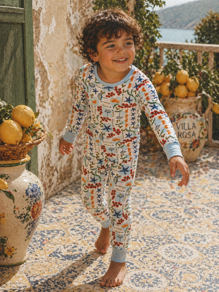 Smiling child in colorful pajamas, walking on a patterned tiled floor beside a basket of lemons.