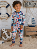 Smiling child in nautical-themed pajamas poses on a sandy beach background with decorative elements.
