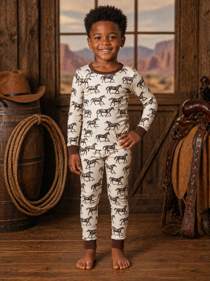 Smiling child in horse-patterned pajamas, standing indoors with a rustic background.