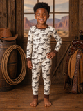 Smiling child in horse-patterned pajamas, standing indoors with a rustic background.