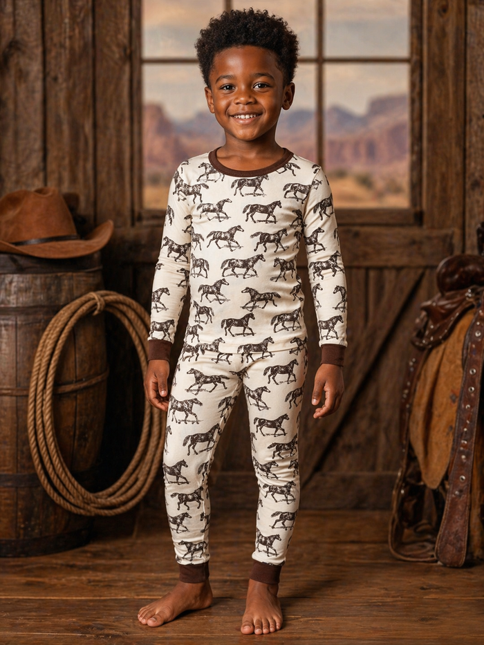 Smiling child in horse-pattern pajamas, standing in a rustic wooden setting with cowboy decor.