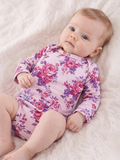 Baby in floral pajamas lying on a soft blanket, looking curiously at the camera.