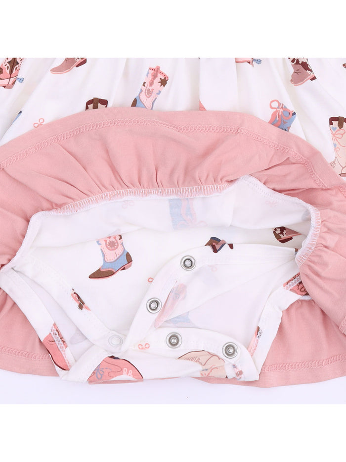 Baby dress with a pink ruffled hem and playful western boot prints on a white background.