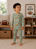 Smiling child in printed pajamas with playful designs, standing in a cozy living room with a football and decor.