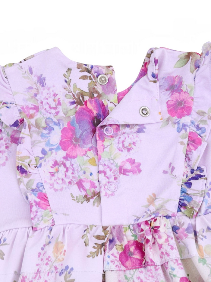 Lilac dress with floral patterns, featuring snaps and ruffled details, perfect for spring or summer wear.