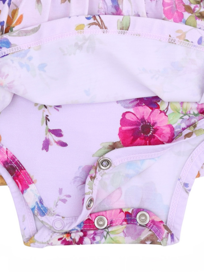 Floral-patterned baby onesie with snap closure at the bottom, featuring shades of purple, pink, and green.