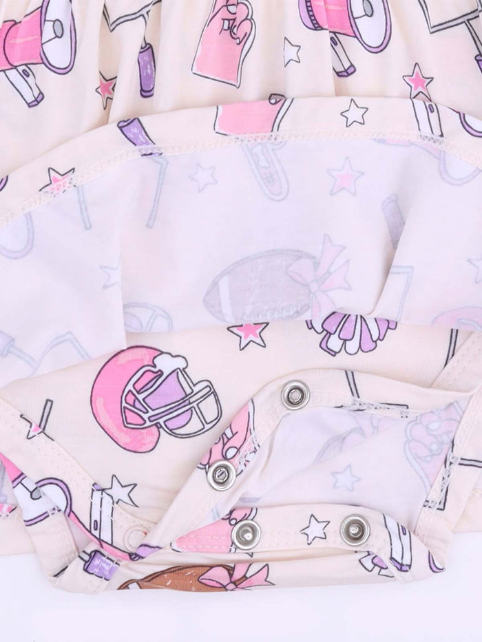 Cute children's outfit with playful patterns of sports, stars, and pom-poms in pink and pastel colors.