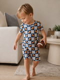 Boy in football-printed pajamas holding a toy football while walking in a cozy living room.