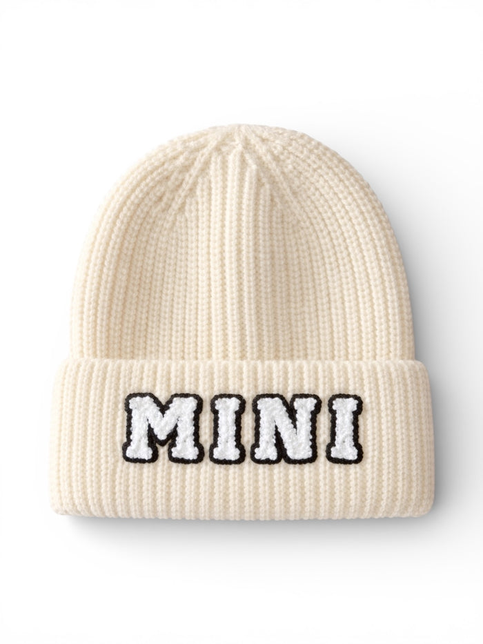 Cream-colored knit beanie with "MINI" embroidered in black and white letters.