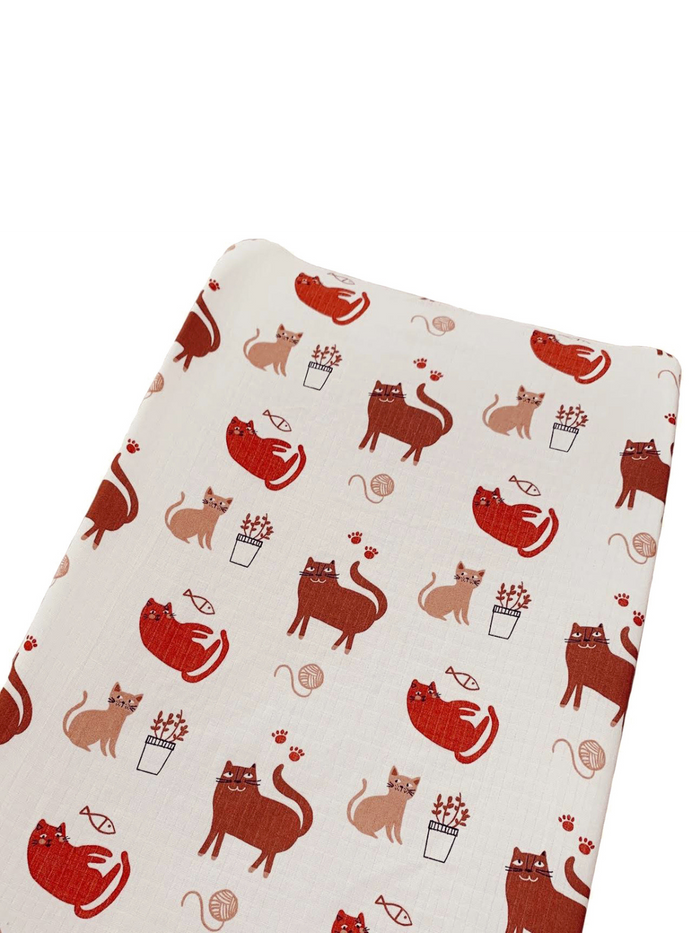 Patterned fabric featuring playful cats in various poses with plants and yarn.