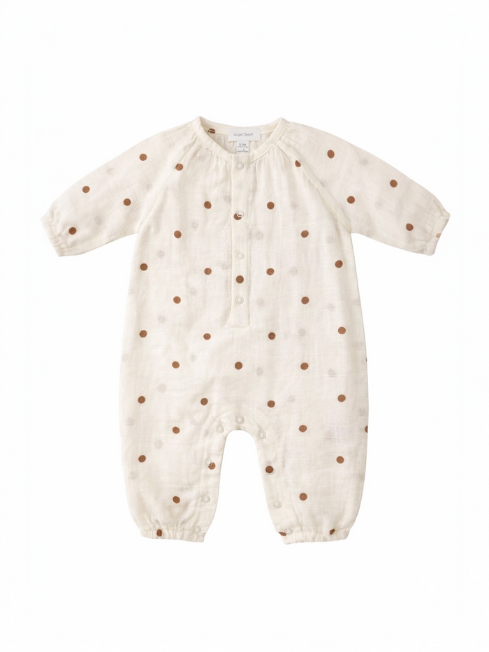 Cream-colored baby romper with brown polka dots and button closure, featuring long sleeves and snap bottom.