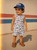 Smiling child in a 'NASA' patterned outfit and USA cap stands on a sidewalk with colorful stripes in the background.