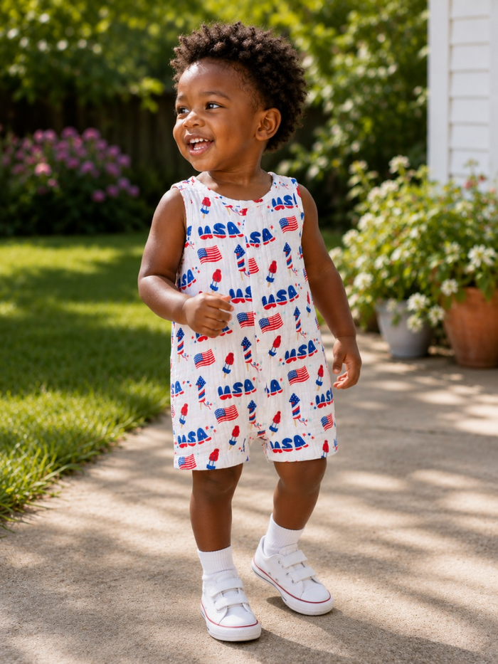 Smiling toddler in a colorful NASA-themed outfit, walking outdoors on a sunny day.