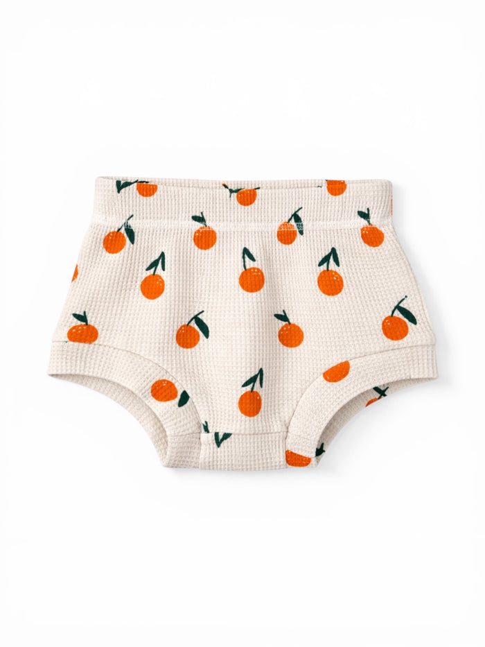 Children's beige shorts with orange fruit patterns and green leaves. Cozy and stylish for casual wear.