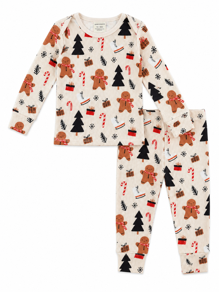 Children's pajamas featuring gingerbread men, Christmas trees, candy canes, and presents on a light background.