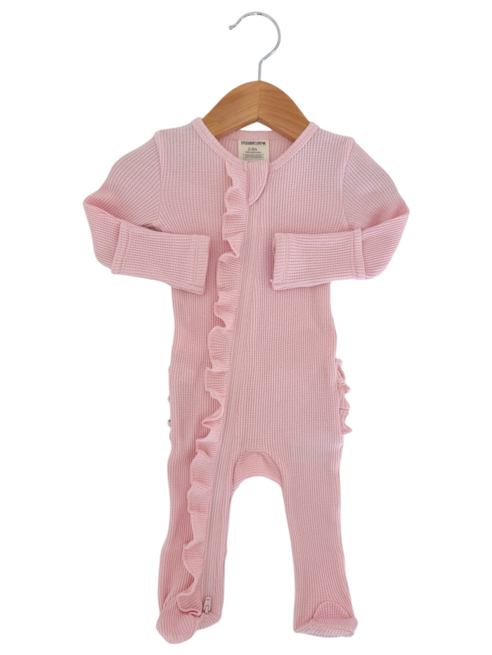 Light pink baby onesie with ruffle detail, hanging on a wooden hanger. Ideal for infants and toddlers.