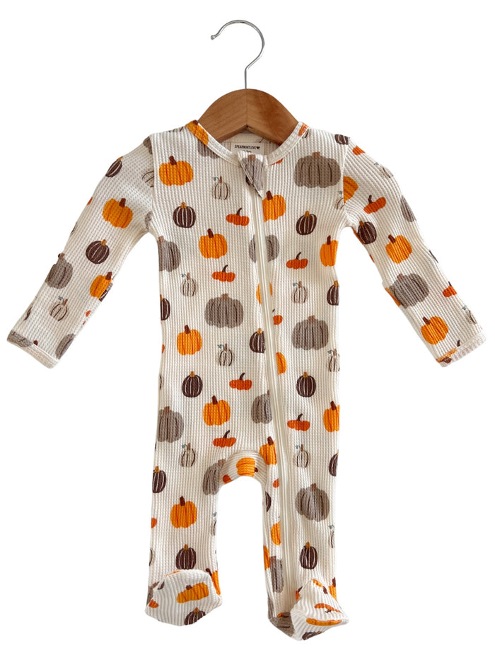 Cute baby onesie with colorful pumpkin prints, hanging on a wooden hanger against a white background.
