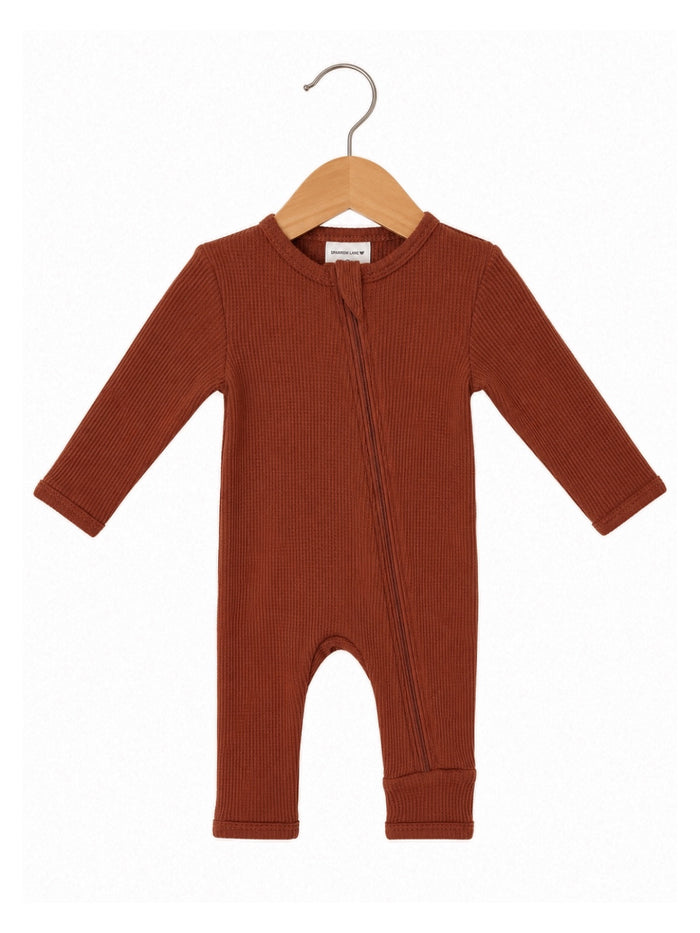 Brown ribbed one-piece baby outfit on a wooden hanger with a zipper front. Ideal for comfort and style.
