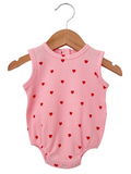 Pink baby onesie with red heart patterns, hanging on a wooden hanger. Ideal for playful, casual wear.