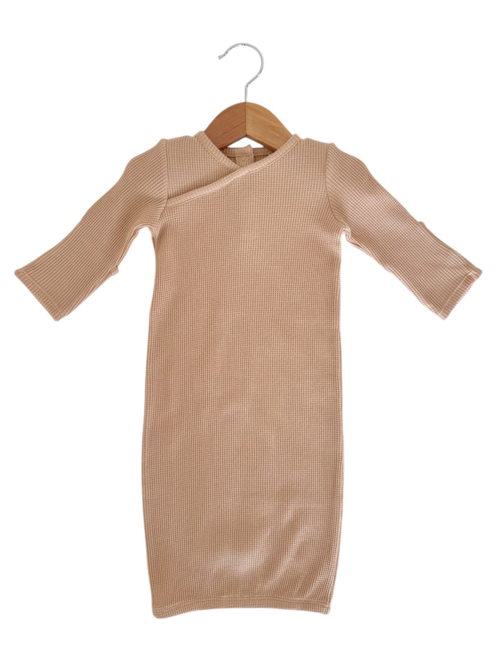 Beige ribbed dress with long sleeves hanging on a wooden hanger against a white background.