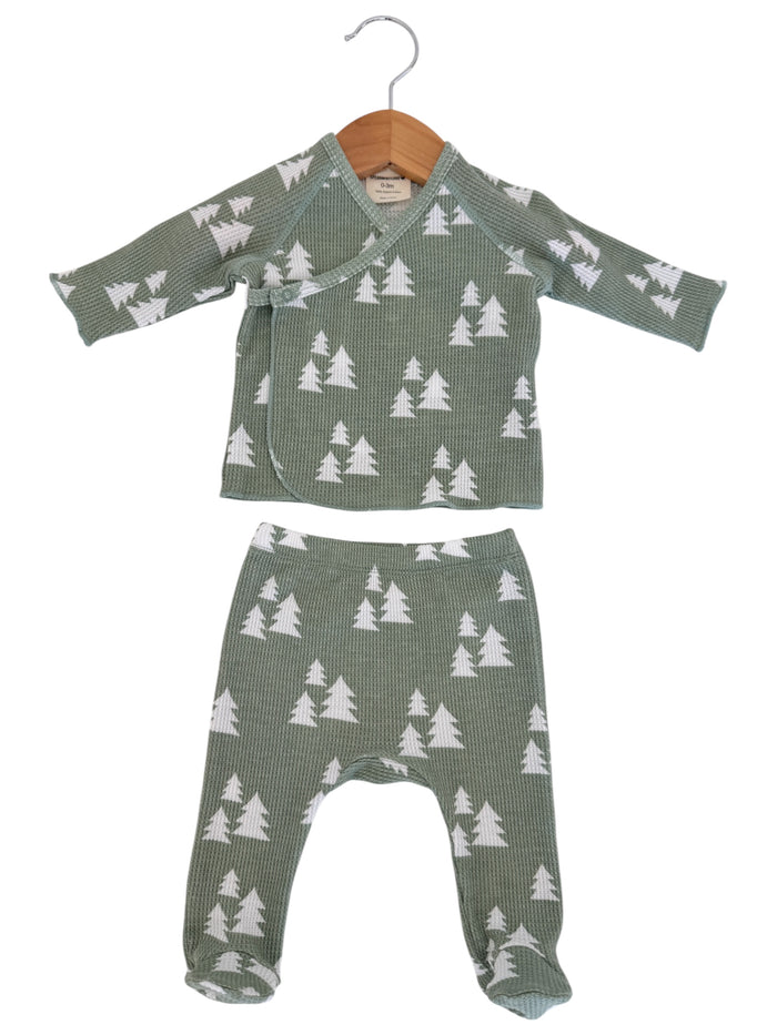 Green baby outfit with long-sleeve top and pants, featuring white tree patterns on a textured fabric.