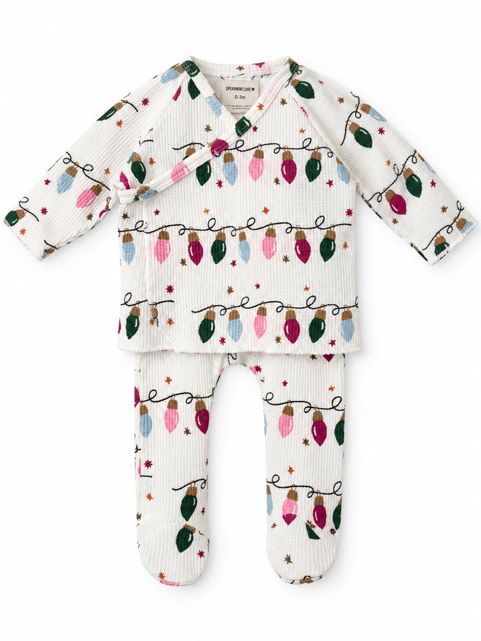 White infant outfit featuring colorful holiday lights pattern, consisting of a long-sleeve top and leggings.