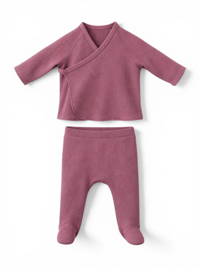 Soft pink ribbed baby outfit featuring a wrap top and matching footed pants. Perfect for comfort and style.