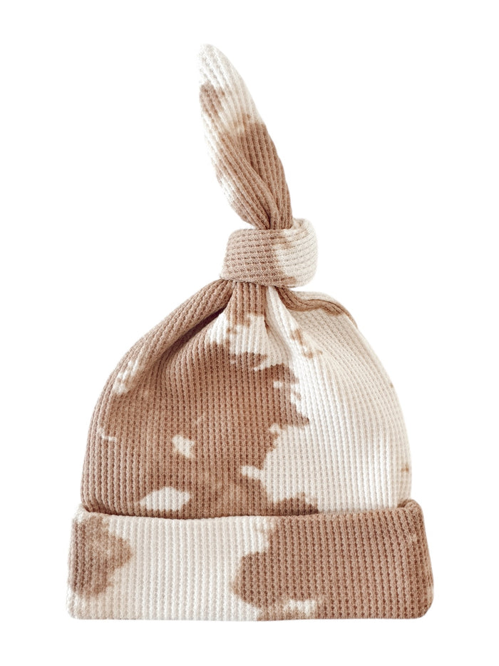 Brown and white tie-dye knit baby hat with a knot on top.