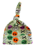 Green skull-patterned hat with knots, featuring colorful skulls and crossbones design.