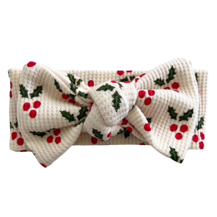 White headband with red berries and green leaves pattern, featuring a large bow in the center.