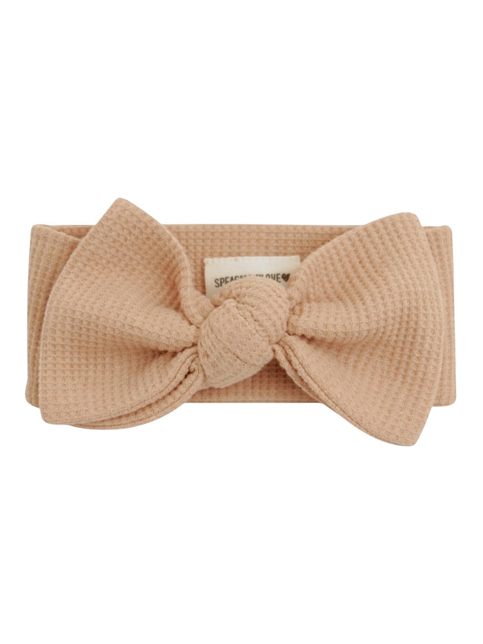 Peach woven headband with a large bow detail at the front and a branded label inside.