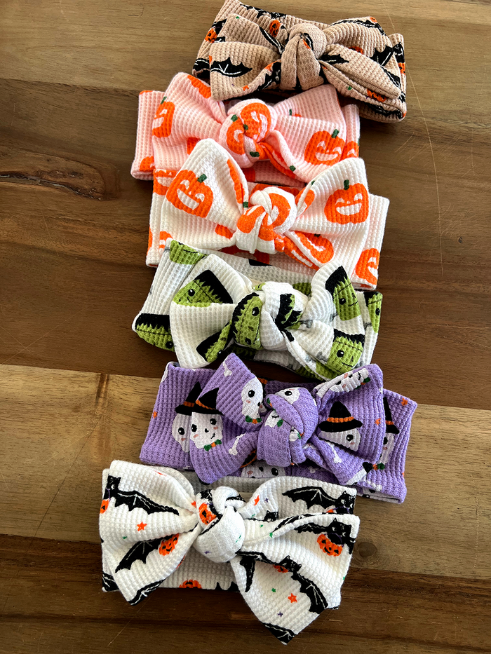 Six colorful Halloween-themed headbands arranged on a wooden surface.