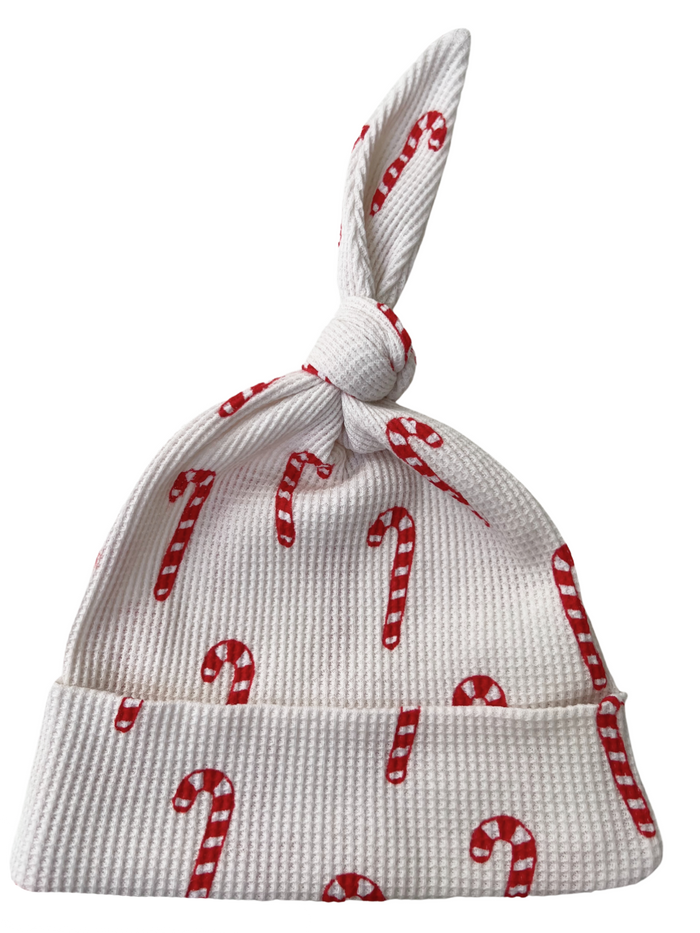 White baby hat with red candy cane pattern and a tied top. Perfect for holiday celebrations.